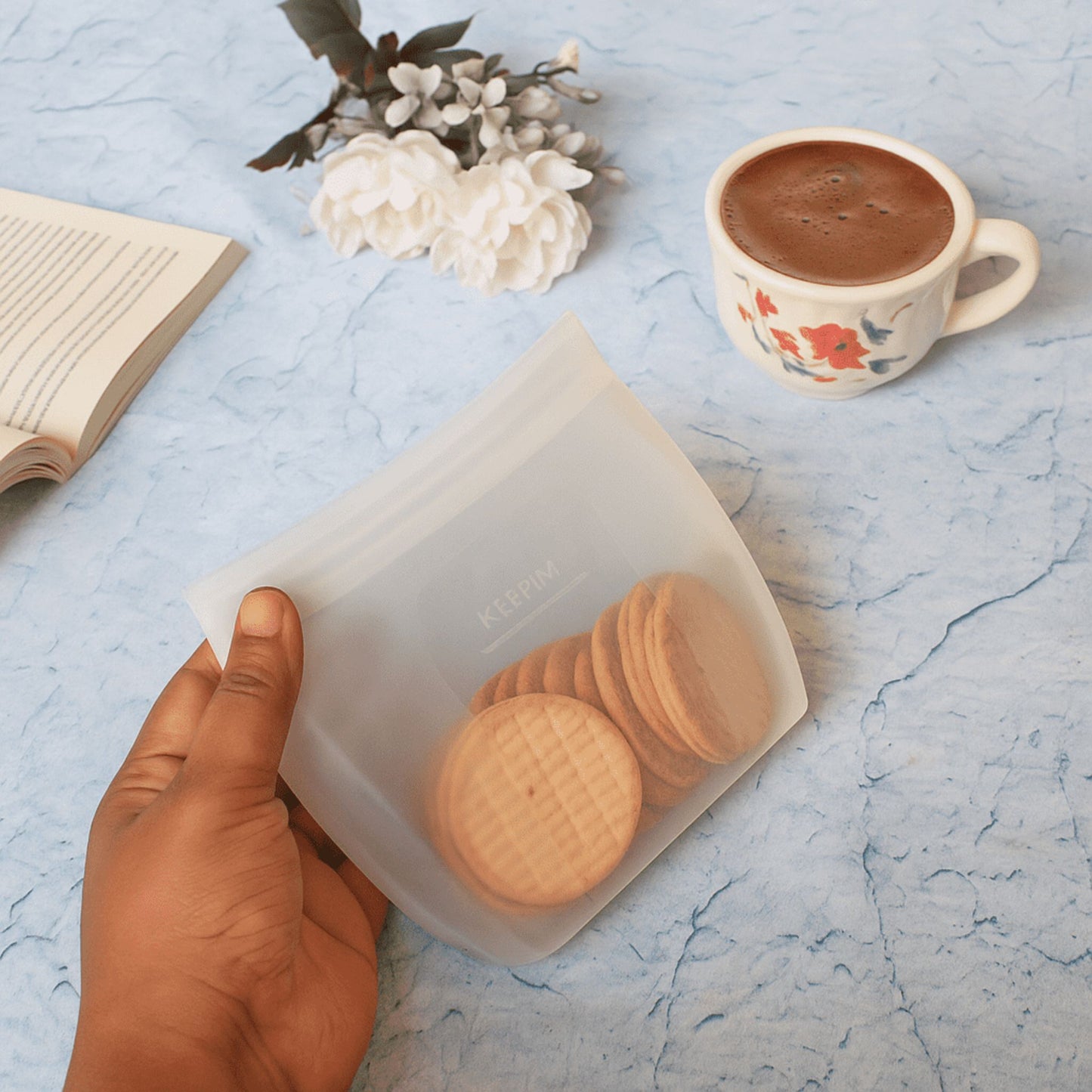 ZipNow Silicone Smart Bag holding cookies next to cup of coffee and open book