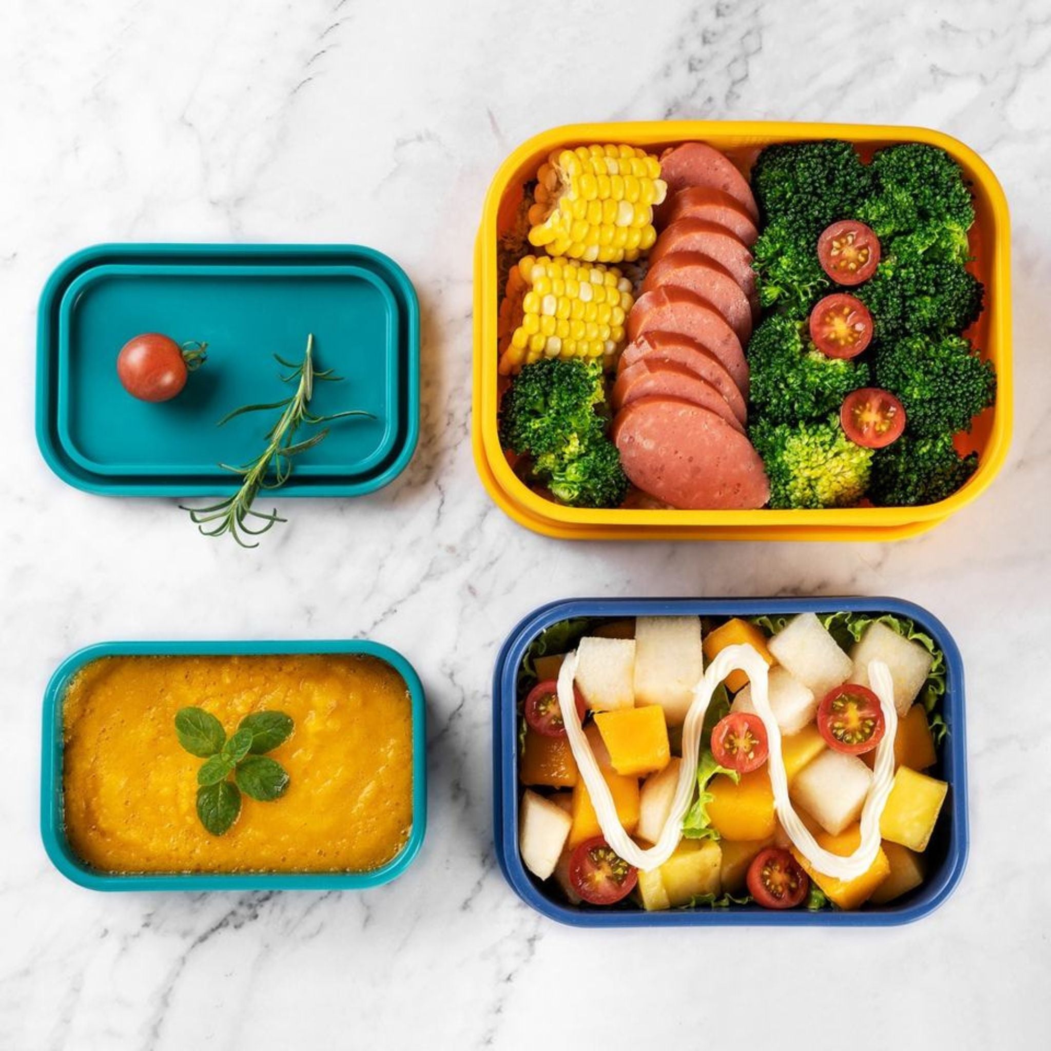 Variety of meals served in ZipNow silicone storage containers on marble countertop
