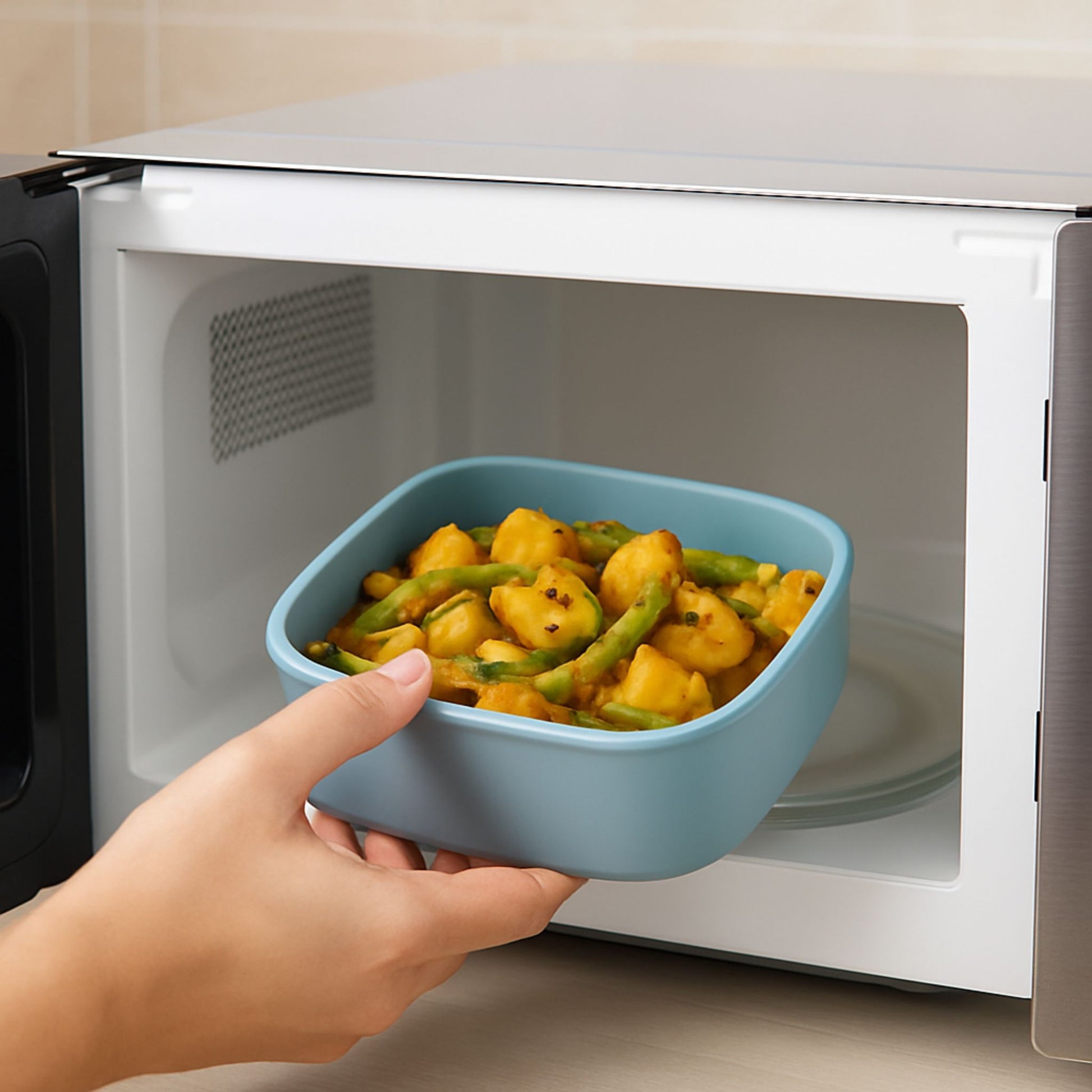 Silicone square container being placed in microwave for heating food
